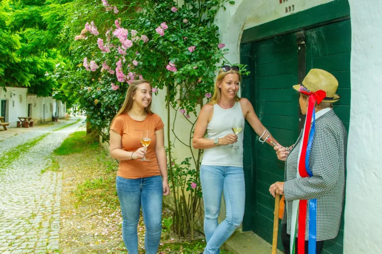 Drei Personen stehen vor einem Keller und trinken Wein - Ausflugsziele im Weinviertel